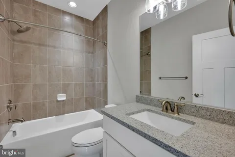 a bathroom with a granite countertop sink a toilet and bathtub