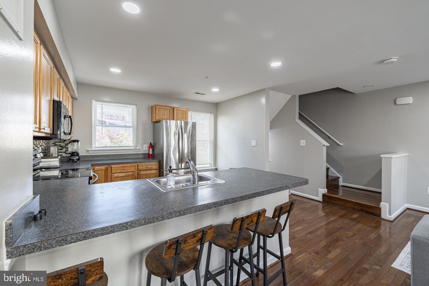 1021 3rd Place Southeast Washington, DC 20003 - Photo 14 of 29 a kitchen with stainless steel appliances granite countertop a sink a stove a dining table and chairs with wooden floor