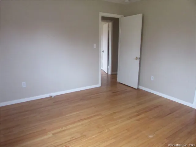 a view of an empty room with wooden floor and bathroom