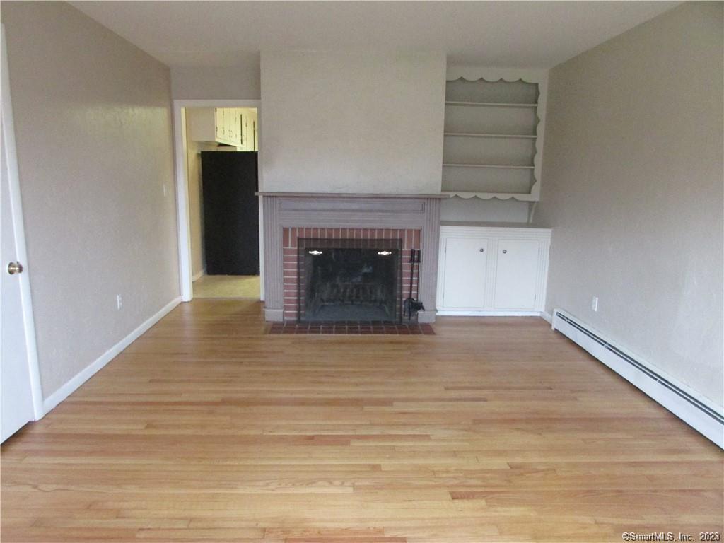 235 Shaker Road Enfield, CT 06082 - Photo 7 of 15 a view of empty room with wooden floor and fireplace