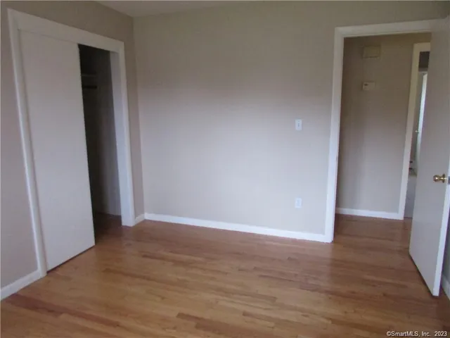 a view of an empty room with wooden floor and closet