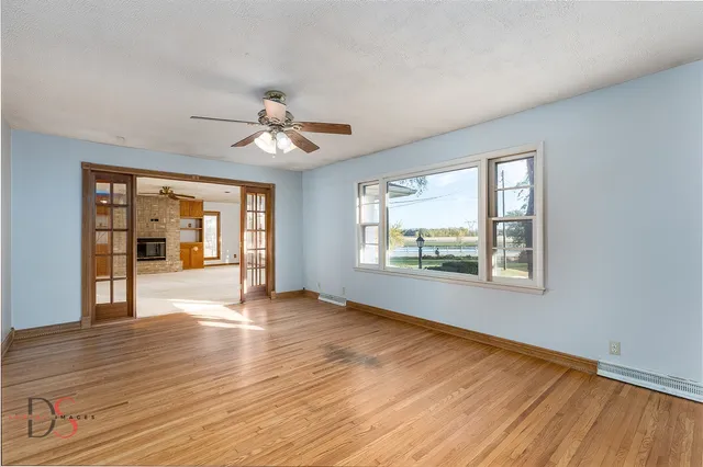 a view of an empty room with a window and wooden floor