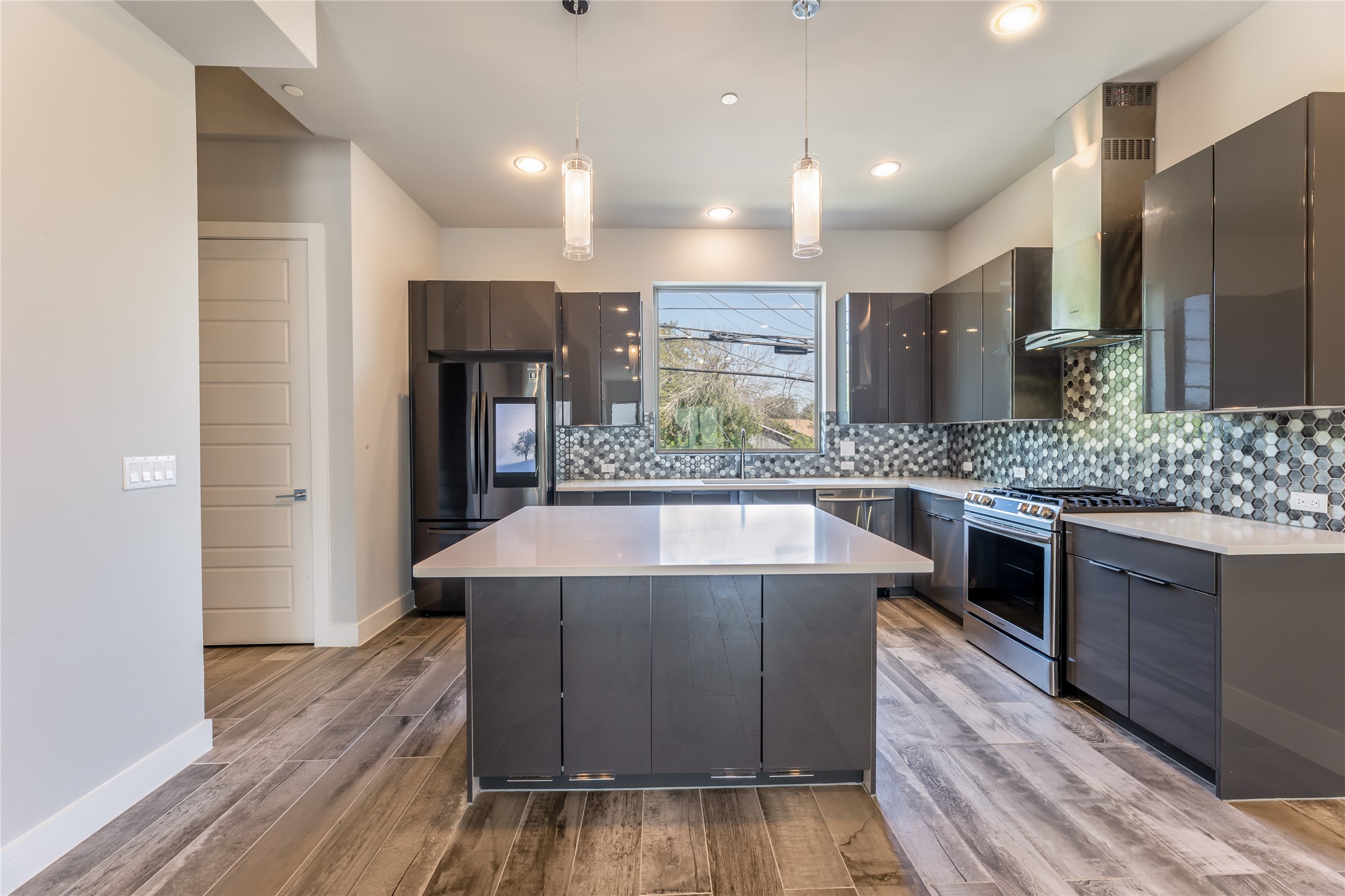 Kitchen with decorative light fixtures, a center island, appliances with stainless steel finishes, decorative backsplash, and modern cabinets