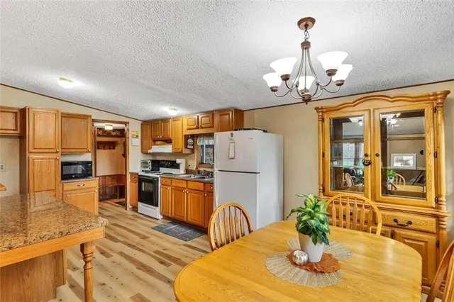 a kitchen with stainless steel appliances granite countertop a refrigerator a stove a kitchen island a dining table and chairs