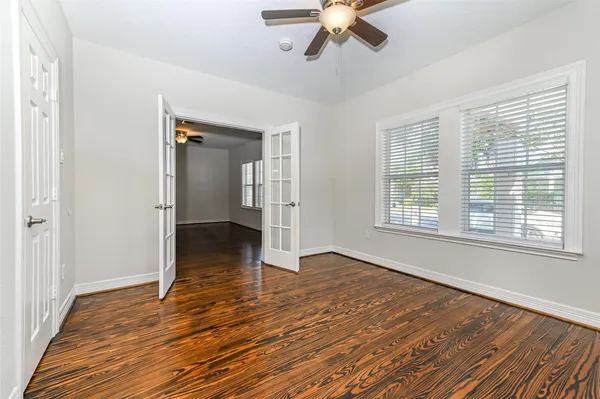 a view of an empty room with wooden floor and a window