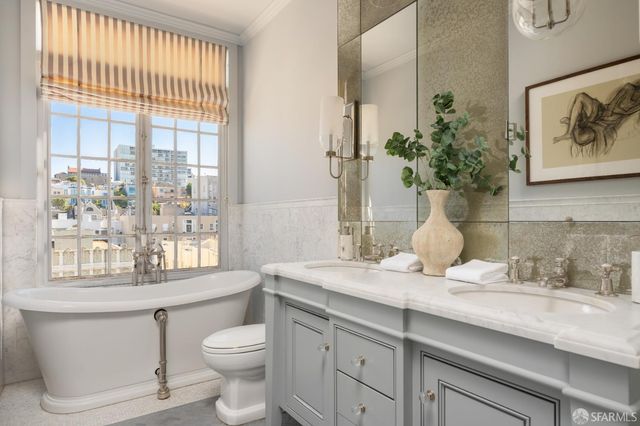 a bath room with a toilet a sink and a large mirror