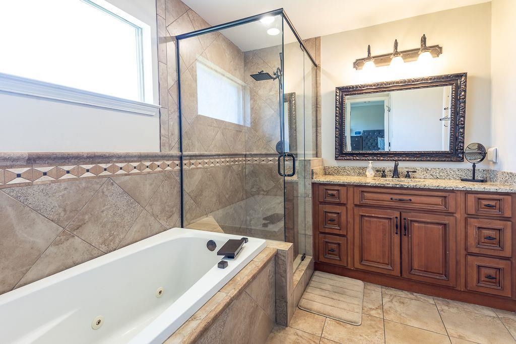 9768 Riggin Drive Memphis, TN 38002 - Photo 19 of 32 Bathroom featuring a jetted tub, glass-enclosed shower, wood vanity with granite countertop, and decorative wall tiling