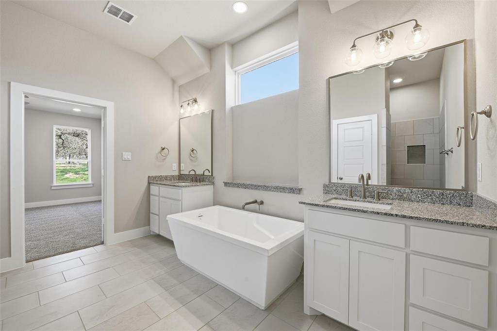 1973 Johnnie Drive Springtown, TX 76082 - Photo 21 of 38 Bathroom with healthy amount of natural light, a freestanding bath, two vanities, light tile patterned floors, and recessed lighting