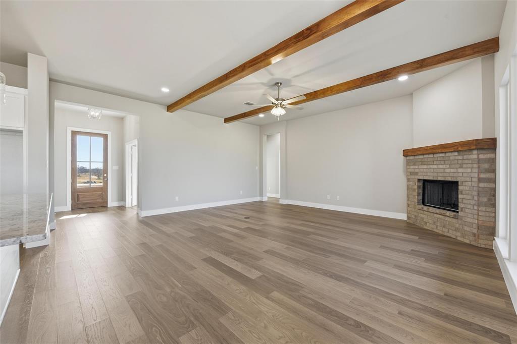 1973 Johnnie Drive Springtown, TX 76082 - Photo 8 of 38 Unfurnished living room with a fireplace, beam ceiling, recessed lighting, light wood finished floors, and a ceiling fan