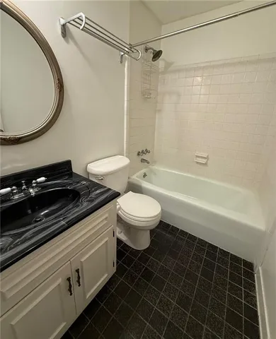 a bathroom with a granite countertop toilet sink and mirror