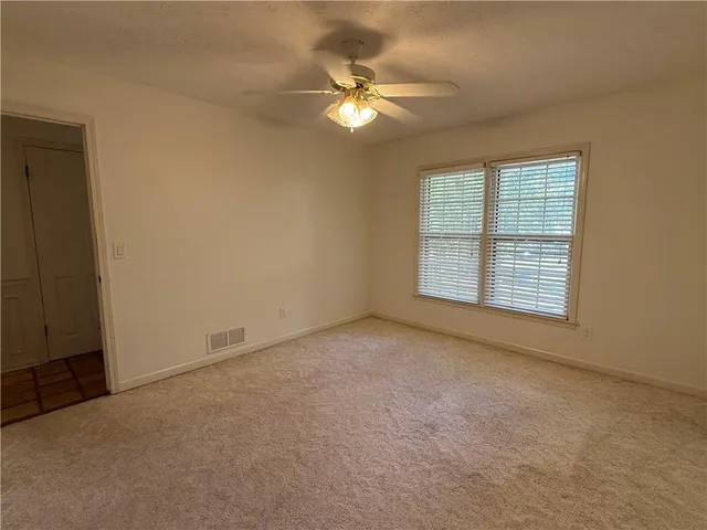 an empty room with windows and fan