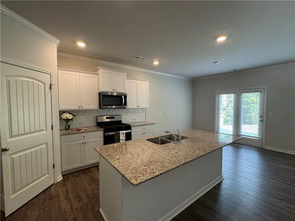 a kitchen with granite countertop kitchen island sink stove and wooden floor