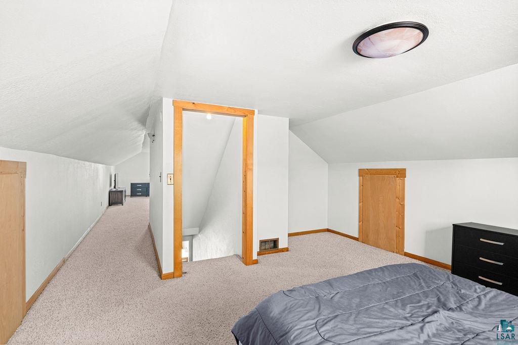 3949 East County Rd B Superior, WI 54880 - Photo 35 of 50 Expansive carpeted floor with sloped ceilings and light wood trim