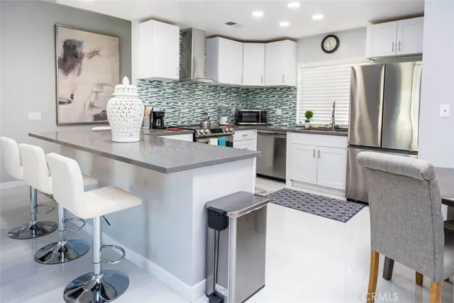 a kitchen with stainless steel appliances kitchen island a table chairs in it and wooden floors