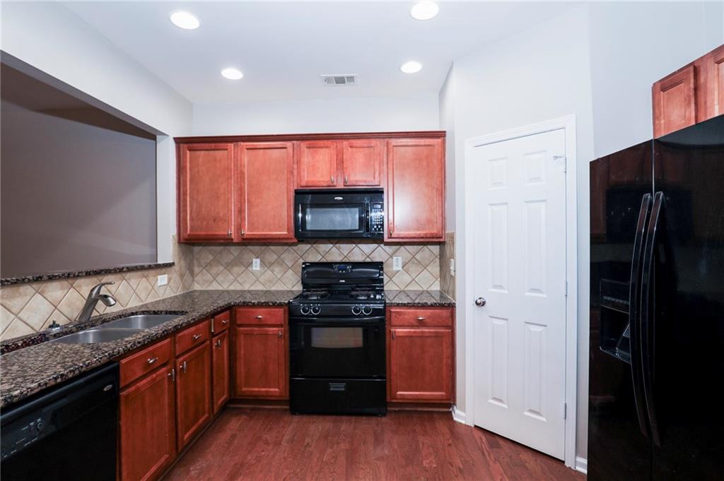 346 Beynon Terrace Suwanee, GA 30024 - Photo 13 of 17 a kitchen with stainless steel appliances granite countertop a stove top oven a sink and dishwasher with wooden floor