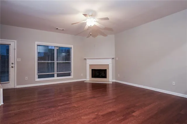 a view of an empty room with wooden floor fireplace and a window