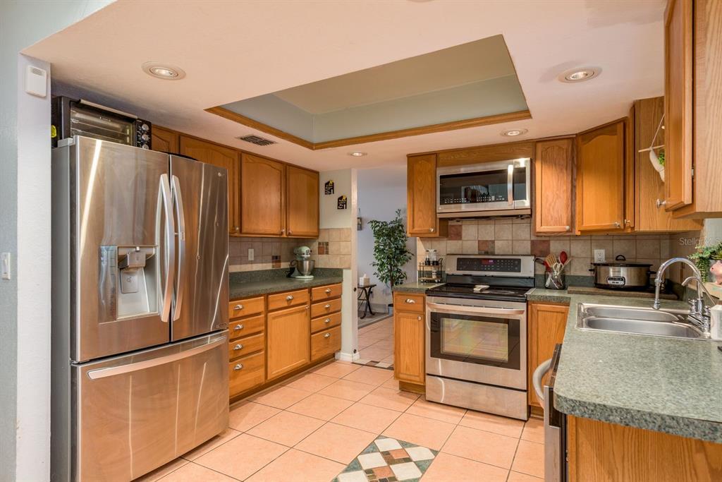 7487 Alhambra Court Spring Hill, FL 34606 - Photo 15 of 61 a kitchen with stainless steel appliances granite countertop a refrigerator stove microwave and sink