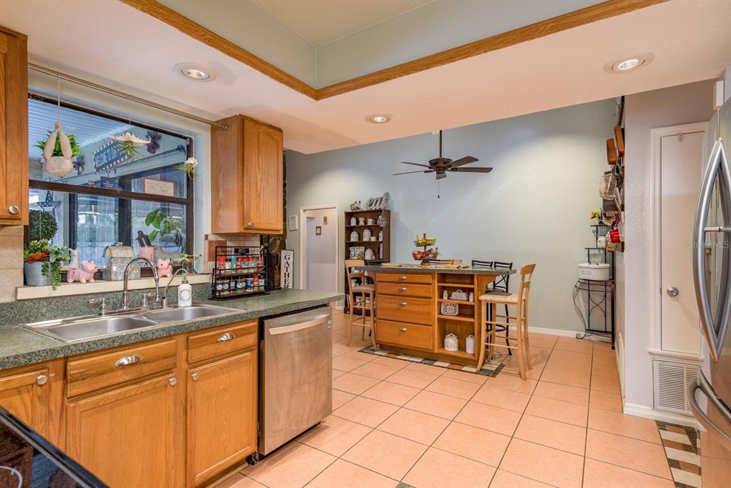 7487 Alhambra Court Spring Hill, FL 34606 - Photo 19 of 61 a kitchen with stainless steel appliances kitchen island granite countertop a refrigerator and cabinets