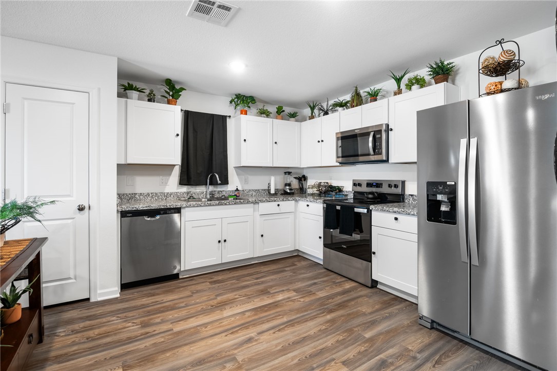 3623 East Andrea Drive Kingman, AZ 86409 - Photo 12 of 40 Kitchen featuring white cabinetry, granite countertops, stainless steel appliances, and wood-look flooring