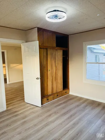 an empty room with wooden floor windows and entrance