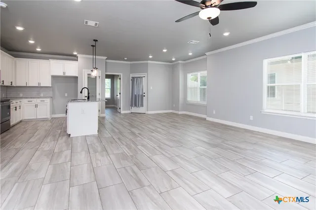 a view of a kitchen with kitchen island stainless steel appliances wooden floor and a refrigerator