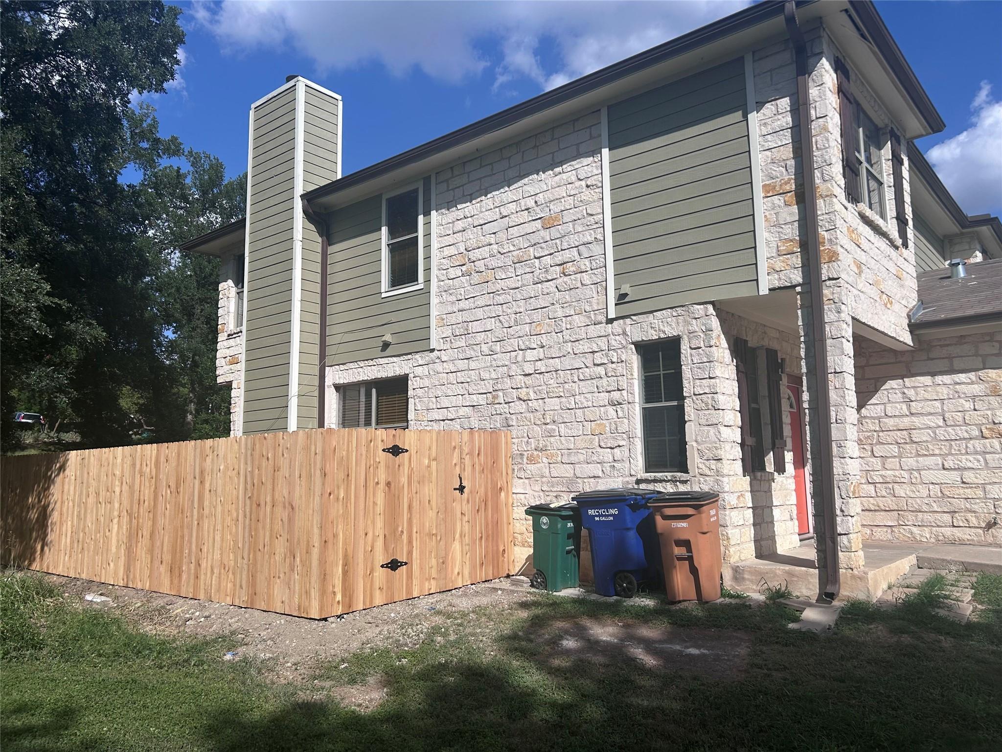 5708 Spring Meadow Road, Unit B Austin, TX 78744 - Photo 19 of 23 Rear view of house featuring stone siding and a chimney