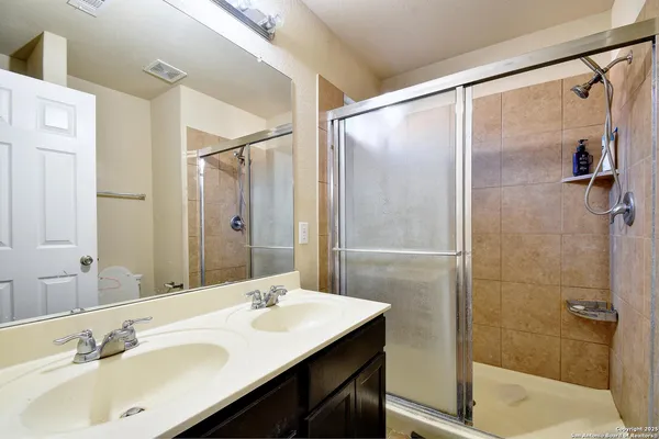 a bathroom with a sink shower and a mirror
