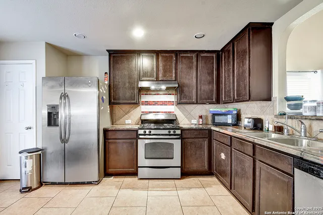 a kitchen with stainless steel appliances granite countertop a stove top oven a sink and dishwasher