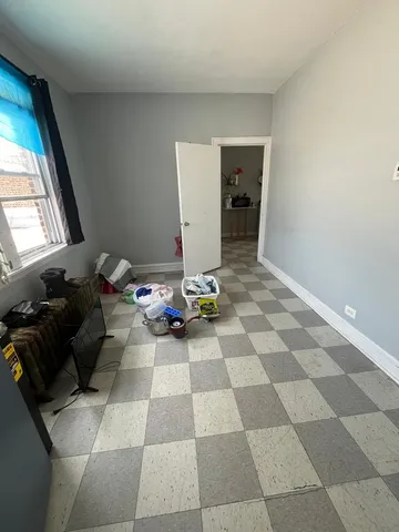 a living room with a black white checkered floor with a gaming machine and dining table