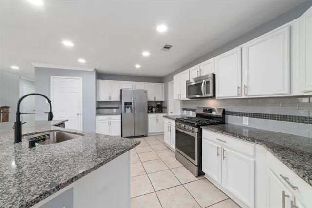 a large kitchen with granite countertop a stove a sink a microwave and refrigerator