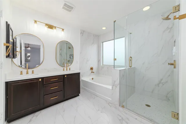 a bathroom with a double vanity sink mirror and bathtub