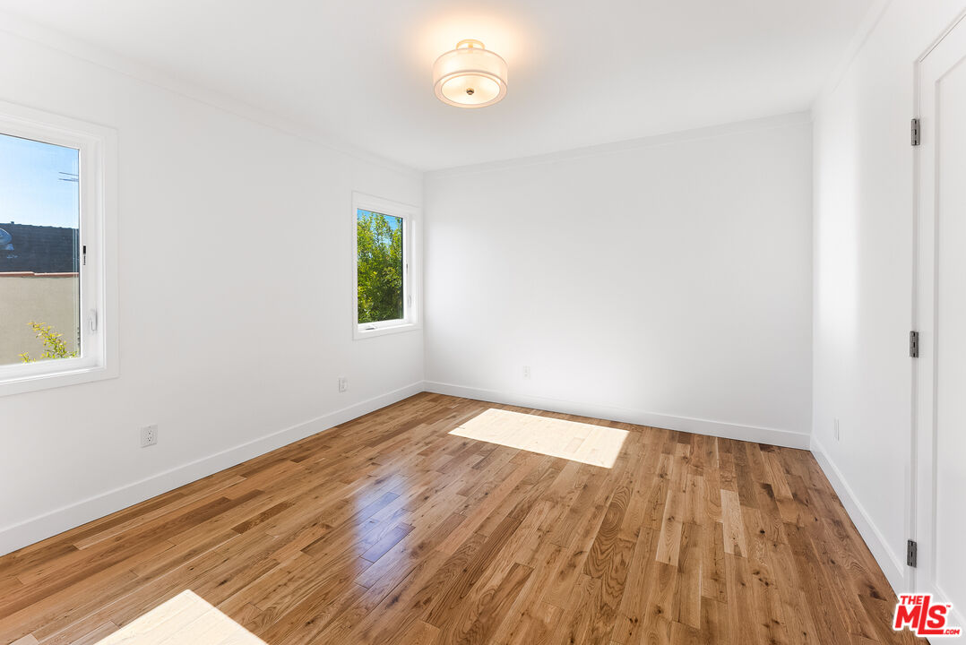 1253 South Rimpau Boulevard Los Angeles, CA 90019 - Photo 30 of 71 an empty room with wooden floor and windows
