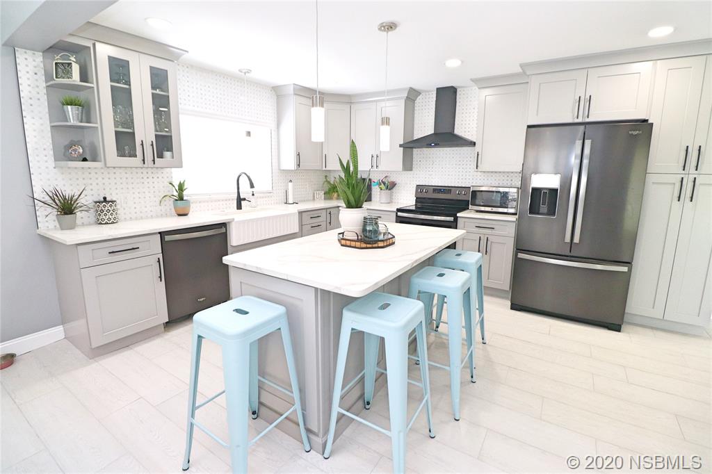 129 Rhode Island Street Edgewater, FL 32132 - Photo 12 of 49 a kitchen with a sink a refrigerator and white cabinets