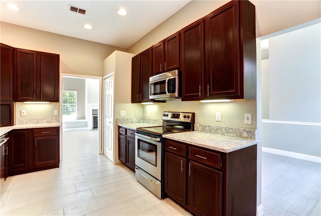 96921 Blackrock Road Yulee, FL 32097 - Photo 4 of 34 a kitchen with stainless steel appliances granite countertop wooden cabinets a stove top oven a sink and dishwasher