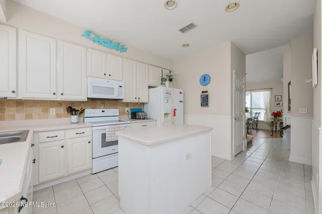 a kitchen with white cabinets and white appliances