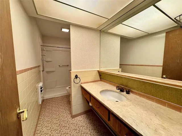 a bathroom with a granite countertop sink a toilet and shower