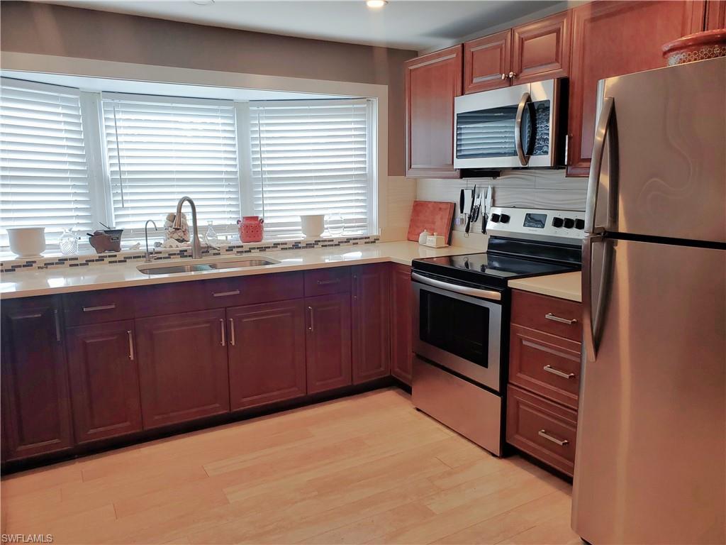 7 Topaz Lane, Unit T7 Naples, FL 34112 - Photo 3 of 23 a kitchen with stainless steel appliances granite countertop a stove a sink dishwasher a refrigerator and a microwave oven