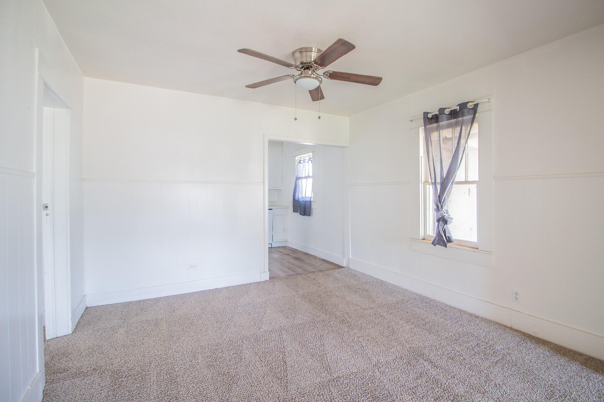 315 South 13th Street Slaton, TX 79364 - Photo 5 of 14 an empty room with a ceiling fan and windows