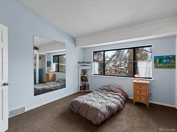 a bed sitting in a spacious bedroom next to a window