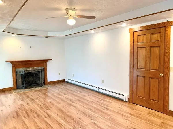 an empty room with wooden floor fireplace and windows