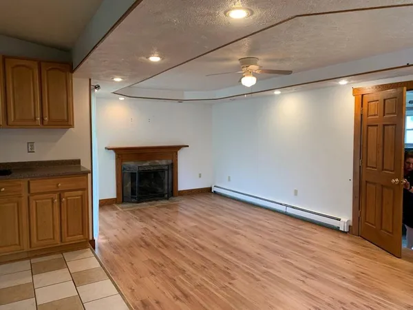 a view of an empty room with wooden floor and a fireplace