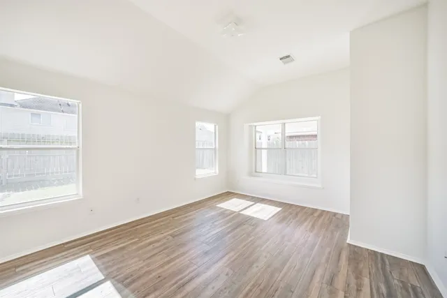 an empty room with wooden floor and windows