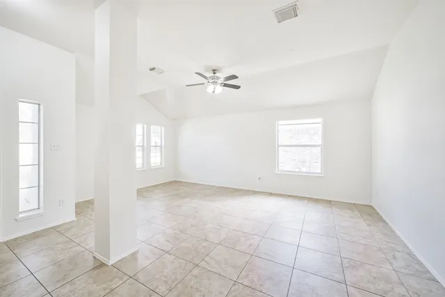 an empty room with windows and ceiling fan