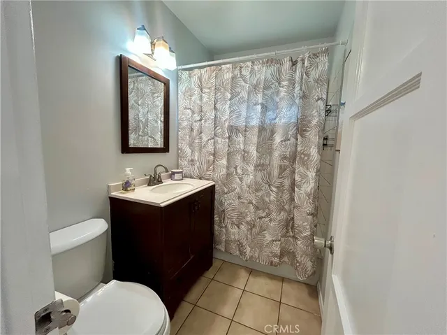 a bathroom with a sink a toilet a mirror and shower curtain