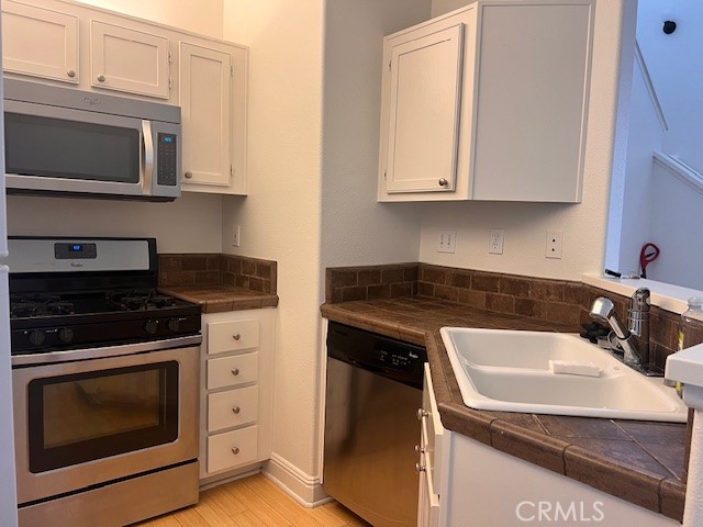 511 Birch Grove Irvine, CA 92618 - Photo 11 of 15 a kitchen with granite countertop white cabinets and stainless steel appliances