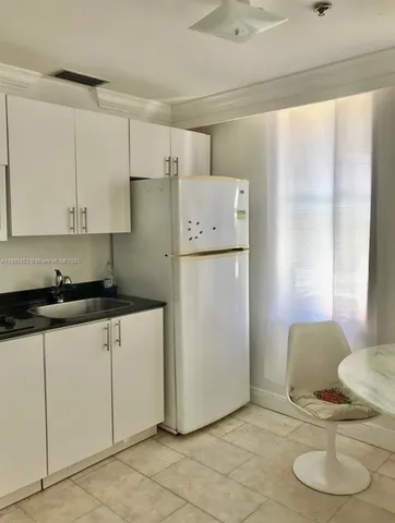 a kitchen with stainless steel appliances granite countertop a refrigerator sink and white cabinets
