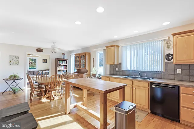 a kitchen with stainless steel appliances granite countertop a stove a sink dishwasher a dining table and chairs with wooden floor