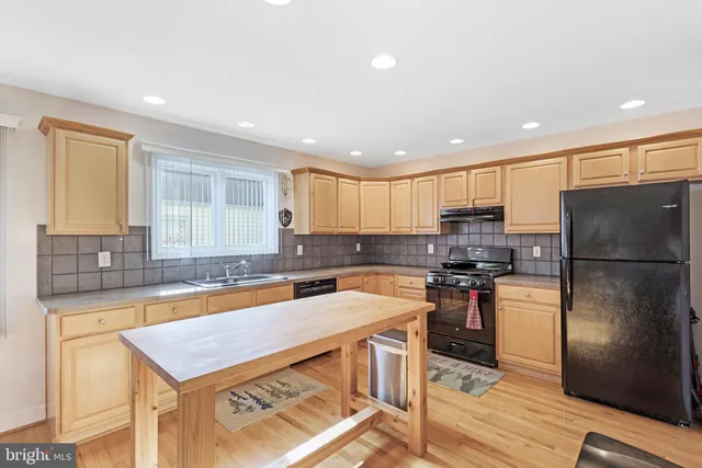 a kitchen with stainless steel appliances granite countertop a refrigerator a stove and a sink with wooden floor