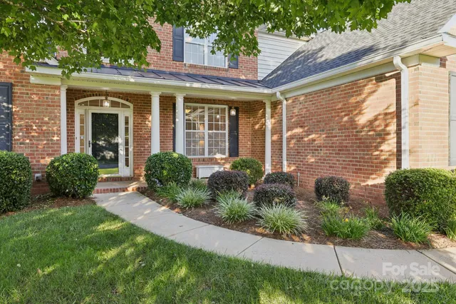 a view of a house with brick walls and a yard with plants