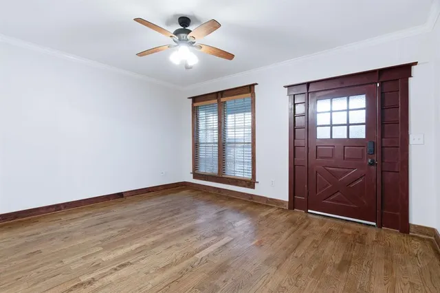 an empty room with wooden floor chandelier fan and windows